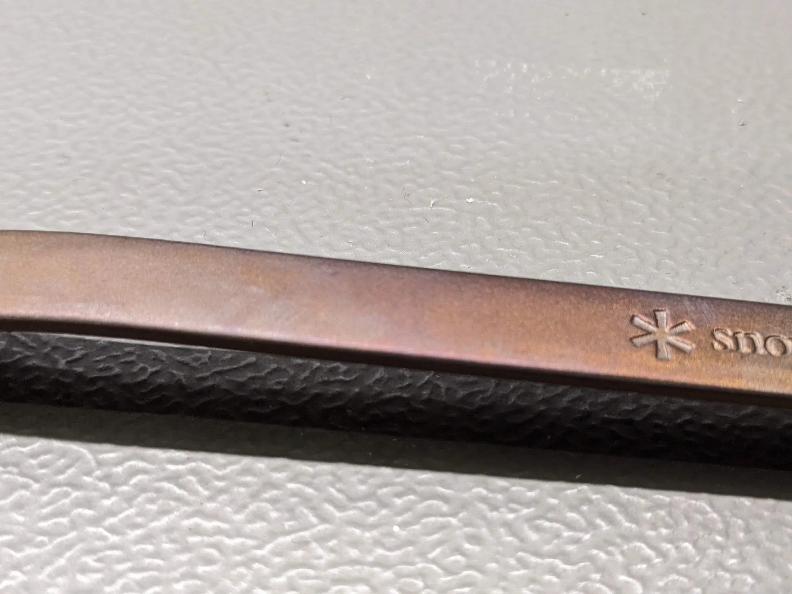 Zoomed in view of a gold/copper coloured spork, with hints of purple